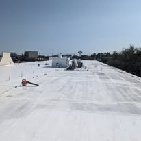 Flat commercial roof receiving a white protective coating